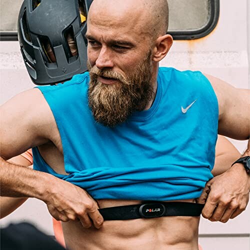 Bearded man adjusting a heart rate monitor on his chest.